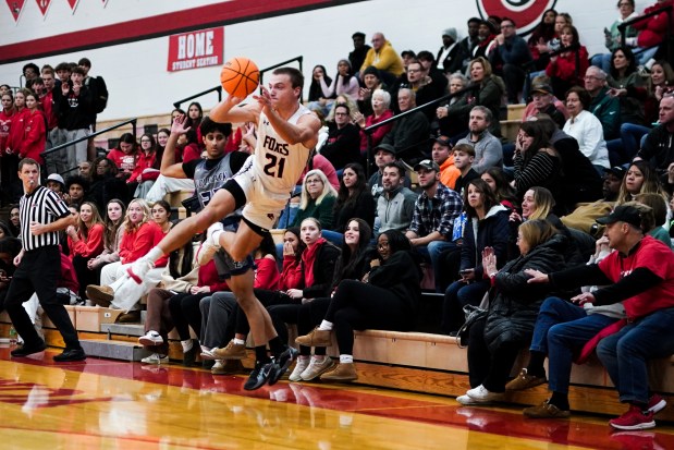 Yorkville's Taelor Clements (21) leaps in the air to save the ball from going out of bounds against Oswego East's Zayn Manalodi (30) during a basketball game at Yorkville High School on Friday, Dec. 13, 2024. (Sean King / for The Beacon-News)