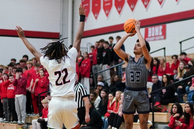 Oswego East's Michael Rembert (33) shoots a three pointer over Yorkville's Braydon Porter (22) during a basketball game at Yorkville High School on Friday, Dec. 13, 2024. (Sean King / for The Beacon-News)