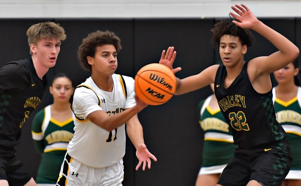 Metea Valley's Anthony Hildreth passes the ball from between Waubonsie Valley defenders Cade Valek and Kris Mporokoso (22) during a game on Friday, Dec. 6, 2024 in Aurora...(Jon Cunningham/for The Beacon-News)