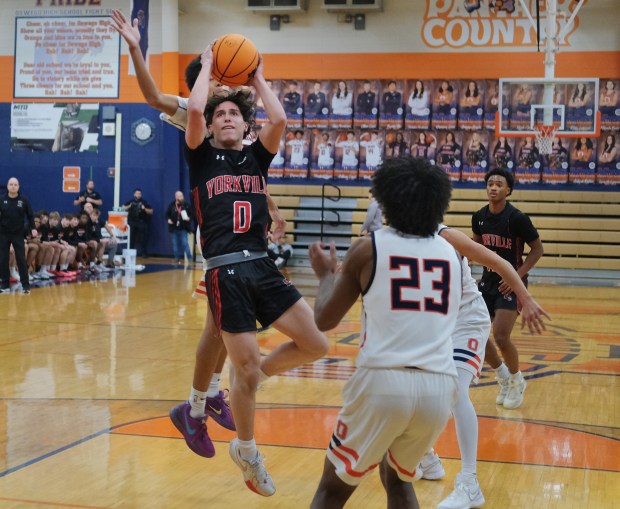 Yorkville's Gabe Sanders (0) goes up to shoot as he is about to be fouled from behind by Oswego's Ethan Vahl during a game on Tuesday, Dec. 10, 2024 in Oswego...(Jon Cunningham/for The Beacon-News)