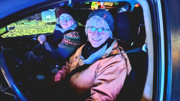 Debbie Berger of Batavia sits in the driver's seat next to her friend Sarah Engel of Aurora who both came to see the light show at the home of Brett Foy at 969 Ekman Drive in Batavia on Tuesday night. (David Sharos / For The Beacon-News)