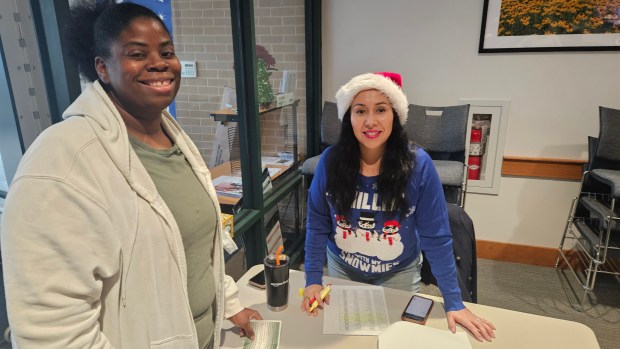 Aurora resident Kimberly Seamon, left, checks in with Salvation Army volunteer Laura Rios Thursday during a toy giveaway event at the Aurora Salvation Army center benefitting people in need in the Aurora-Naperville area. (David Sharos/For The Beacon-News)