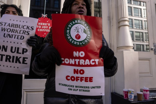 People hold signs outside a closed Starbucks as workers strike on Dec. 23, 2024, in New York. (Adam Gray/Getty)