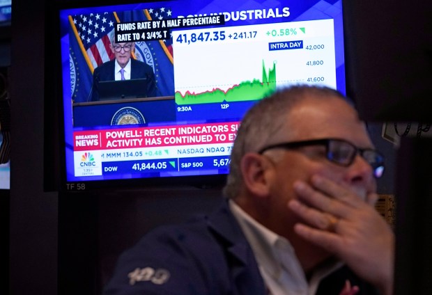 Trader Michale Conlon, right, works on the floor of the New York Stock Exchange as Federal Reserve Chair Jerome Powell's news conference appears on a television screen behind him on Sept. 18, 2024. (Richard Drew/AP)