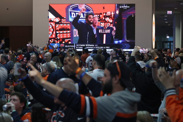 Caleb Williams of USC is projected on a screen as the first 2024 NFL Draft pick by the Chicago Bears, as Bears fans cheer during a watch party at Soldier Field on April 25, 2024, in Chicago. (John J. Kim/Chicago Tribune)