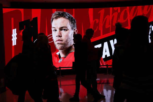 A photo of Chicago Blackhawks left wing Taylor Hall (71) sits on a screen while fans walk though the concourse before the Blackhawks play the Washington Capitals during the first period at the United Center Tuesday Dec. 17, 2024, in Chicago. (Armando L. Sanchez/Chicago Tribune)