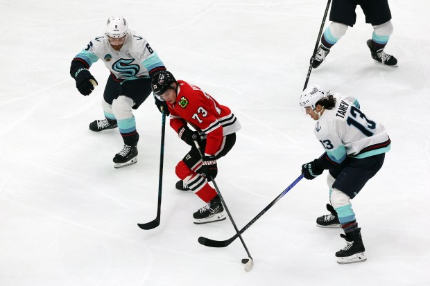 Blackhawks left wing Lukas Reichel (73) handles the puck as Kraken defenseman Adam Larsson (6) and Kraken left wing Brandon Tanev (13) chase him in the first period at the United Center in Chicago on Dec. 19, 2024. (Terrence Antonio James/Chicago Tribune)