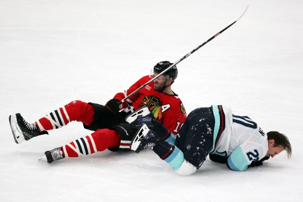 Blackhawks center Jason Dickinson (16) and Kraken right wing Eeli Tolvanen (20) crash to the ice in the second period at the United Center in Chicago on Dec. 19, 2024. (Terrence Antonio James/Chicago Tribune)