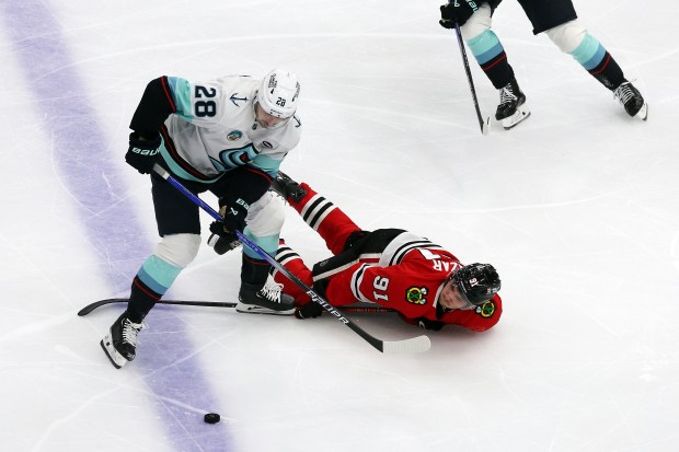 Kraken defenseman Joshua Mahura (28) trips Blackhawks center Frank Nazar (91) in the second period at the United Center in Chicago on Dec. 19, 2024. (Terrence Antonio James/Chicago Tribune)