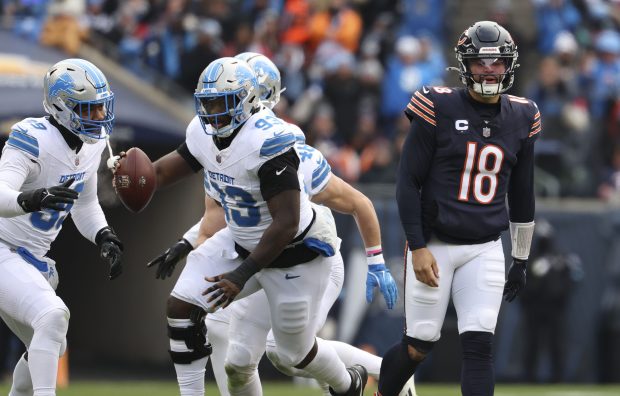 Bears quarterback Caleb Williams walks off while Lions defensive end Josh Paschal (93) celebrates a fumble recovery in the first quarter Sunday, Dec. 22, 2024, at Soldier Field. (Brian Cassella/Chicago Tribune)