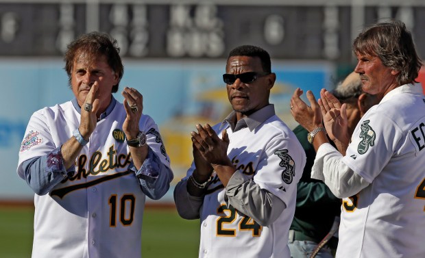 Former Oakland Athletics, from left, manager Tony La Russa, Rickey Henderson and Dennis Eckersley applaud during a pregame ceremony honoring the 1989 World Series champions on July 19, 2014, in Oakland, Calif. (AP Photo/Ben Margot)