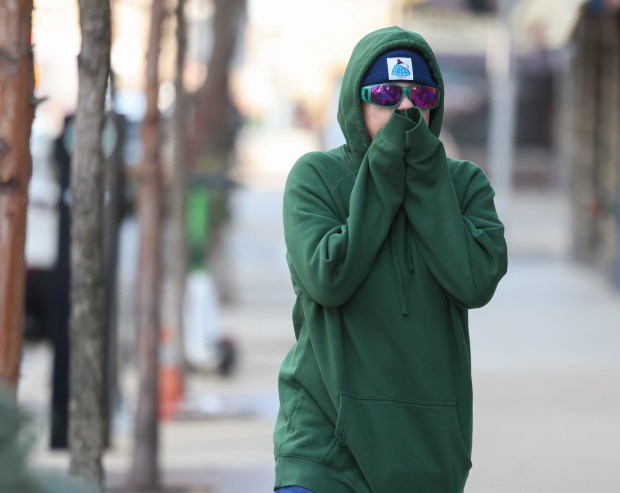 A visitor from St. Louis, name not given, blows into her sweatshirt sleeves to keep her hands warm while walking to a convenience story in the 500 block of West Diversey Parkway on Nov. 30, 2024. (John J. Kim/Chicago Tribune)