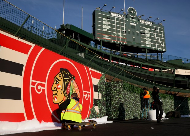 Signage is added to the outfield walls Monday, Dec. 30, 2024 before the Chicago Blackhawks and St. Louis Blues face off in the NHL Winter Classic at Wrigley Field. (Brian Cassella/Chicago Tribune)