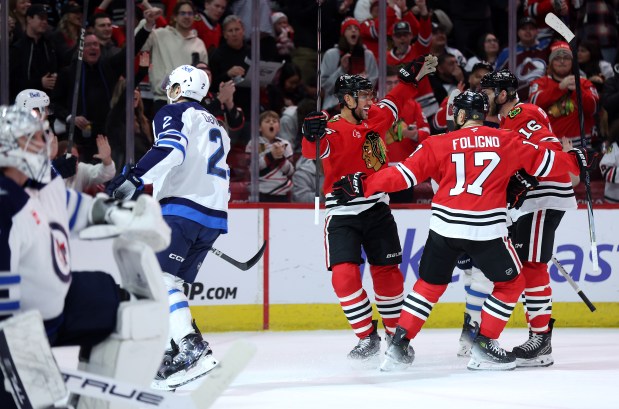 Chicago Blackhawks defenseman Alec Martinez (center) celebrates with teammates Nick Foligno (17) and Jason Dickinson (16) after Martinez scored a goal in the first period of a game against the Winnipeg Jets at the United Center in Chicago on Dec. 7, 2024. (Chris Sweda/Chicago Tribune)