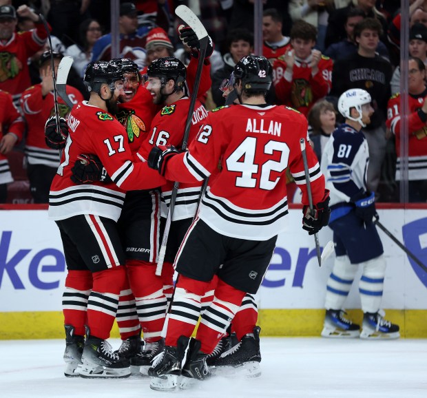 Chicago Blackhawks defenseman Alec Martinez (center) celebrates with teammates Nick Foligno (17) and Jason Dickinson (16) and Nolan Allan (42) after Martinez scored a goal in the first period of a game against the Winnipeg Jets at the United Center in Chicago on Dec. 7, 2024. (Chris Sweda/Chicago Tribune)