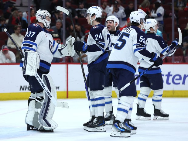 Winnipeg Jets goaltender Connor Hellebuyck (left) celebrates with his teammates after a victory over the Chicago Blackhawks at the United Center in Chicago on Dec. 7, 2024. (Chris Sweda/Chicago Tribune)