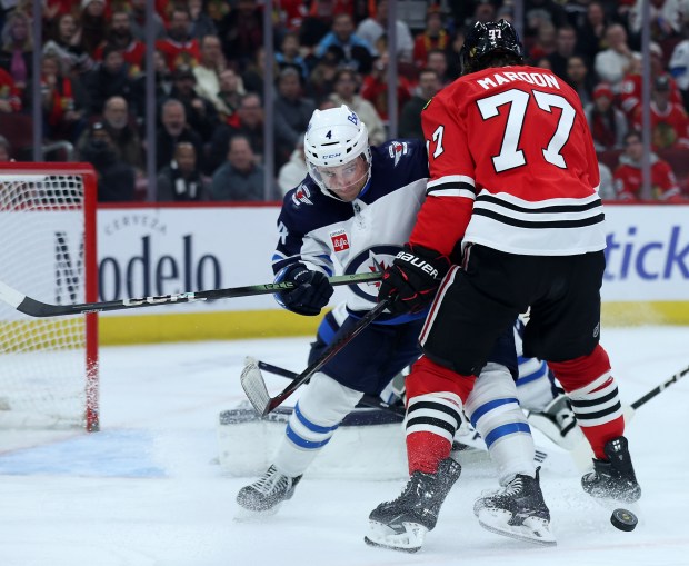 Winnipeg Jets defenseman Neal Pionk (4) and Chicago Blackhawks left wing Patrick Maroon (77) battle in the third period of a game at the United Center in Chicago on Dec. 7, 2024. (Chris Sweda/Chicago Tribune)