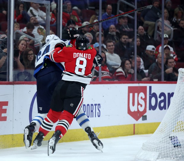 Chicago Blackhawks center Ryan Donato (8) checks Winnipeg Jets defenseman Logan Stanley (64) into the boards in the third period of a game at the United Center in Chicago on Dec. 7, 2024. (Chris Sweda/Chicago Tribune)