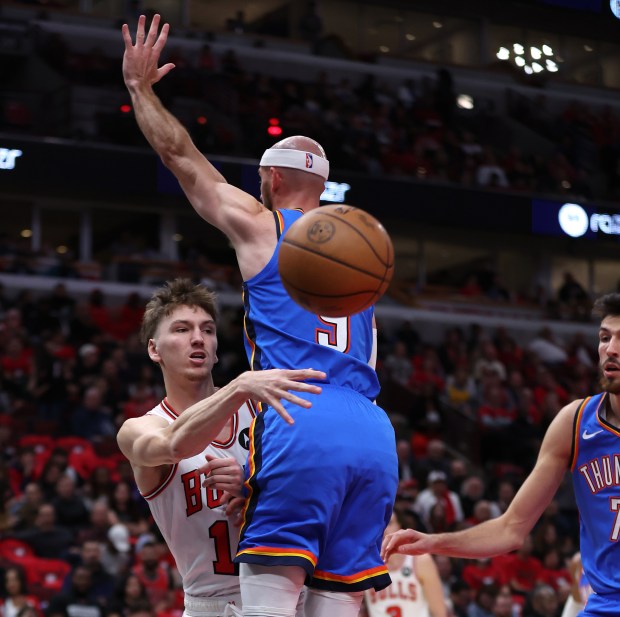 Chicago Bulls forward Matas Buzelis (14) makes a pass around Oklahoma City Thunder guard Alex Caruso (9) in the first half of the Bulls home opener at the United Center in Chicago on Oct. 26, 2024. (Chris Sweda/Chicago Tribune)