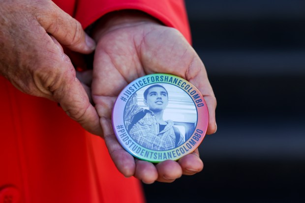 Tonya Colombo holds a button with a photo of her son, Shane Colombo,as she stands in front of the Leighton Criminal Court Building on Oct. 24, 2024. (Eileen T. Meslar/Chicago Tribune)