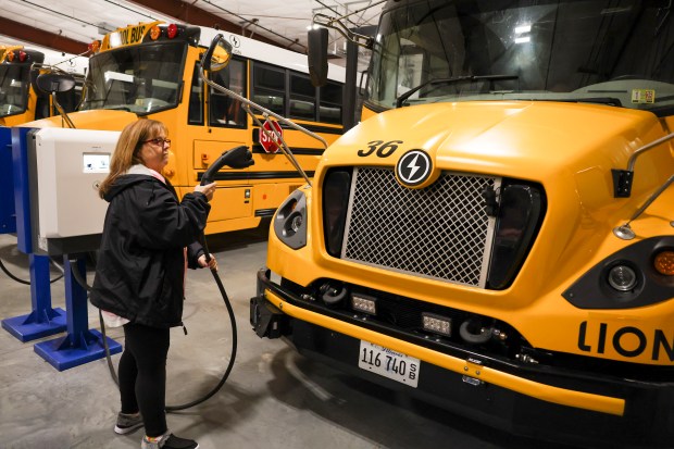 Herscher school district bus driver Jan Anderson prepares to charge the electric school bus she drives on Dec. 17, 2024. (Eileen T. Meslar/Chicago Tribune)