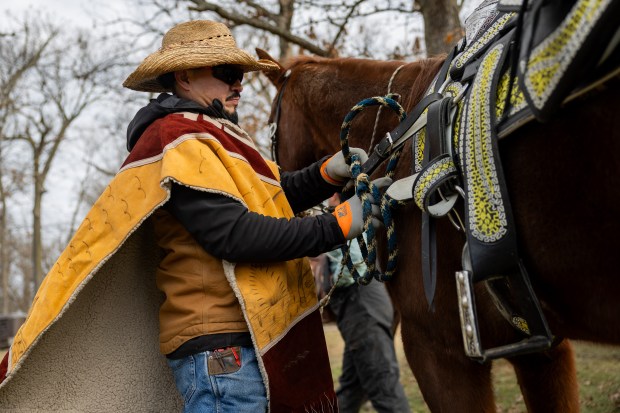 Juan Hernandez, a rider from Club Los Vaqueros Unidos, gets ready for the annual horseback pilgrimage at Dam No. 1 Woods (East) Forest Preserve in Wheeling Dec. 7, 2024. (Tess Crowley/Chicago Tribune)