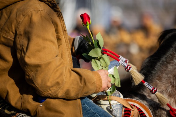 A rider from Club Los Vaqueros Unidos holds a rose to leave at the Shrine of Our Lady of Guadalupe as they finish the horseback pilgrimage at the Shrine of Our Lady of Guadalupe in Des Plaines on Dec. 7, 2024. (Tess Crowley/Chicago Tribune)