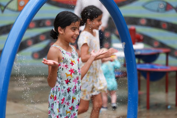 Twins Savannah, left, and Sophia Torres, 10, play in the water at Margaret Donahue Park in Lake View on July 14, 2024. (Eileen T. Meslar/Chicago Tribune)