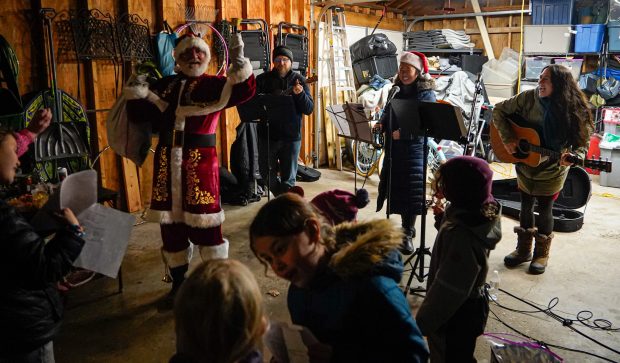 Dan Gazdic, Briana Lee and Nancy Kujawinski lead carols during a holiday block party on Dec. 14, 2024, in Chicago's Lincoln Square neighborhood. (Addison Annis/for the Chicago Tribune)