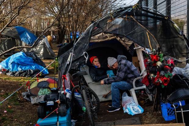 Olivia Hutchison, 29, left, and Richard Thomas Jr., 51, sit in their tent at a homeless encampment near Interstate Highway 74 on Nov. 26, 2024, in Peoria, Illinois. Recently Peoria passed an ordinance that would enforce fines and jail time for people sleeping on the public way. (Armando L. Sanchez/Chicago Tribune)