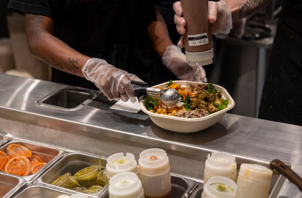 Final ingredients are added to salads after they come off the new Infinite Kitchen robotic system line, Dec. 15, 2024, at Willis Tower. (Brian Cassella/Chicago Tribune)