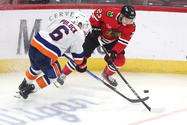 Ryan Pulock #6 of the New York Islanders and Philipp Kurashev #23 of the Chicago Blackhawks work for a loose puck during the third period at the United Center on Dec. 15, 2024 in Chicago, Illinois. (Photo by Stacy Revere/Getty Images)