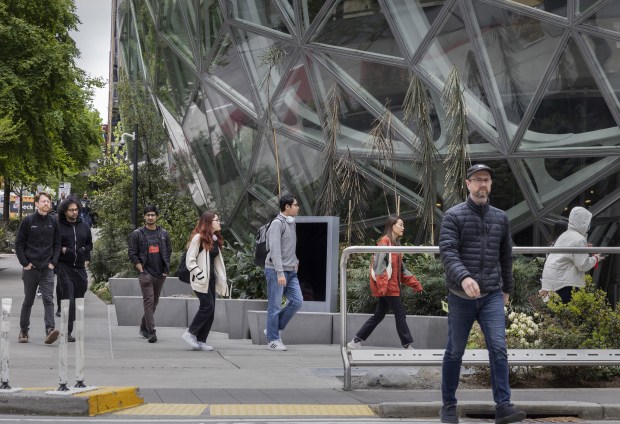 People walk near the Amazon Spheres, which are part of the company campus, in Seattle on May 1, 2023. (Ellen M. Banner/The Seattle Times)