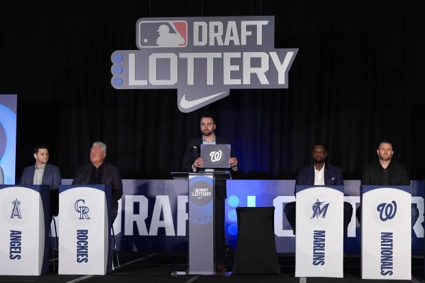 Emcee, Baltimore Orioles outfielder Colton Cowser, holds up the the Washington Nationals logo after the organization won the overall number one pick in the draft lottery at the Major League Baseball winter meetings in Dallas, Tuesday, Dec. 10, 2024. (AP Photo/Tony Gutierrez)