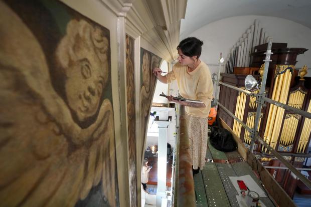 Conservator Corrine Long, of Dover, N.H., restores nearly 300-year-old painted angels on walls of Old North Church, Wednesday, Dec. 18, 2024, in Boston. (AP Photo/Steven Senne)