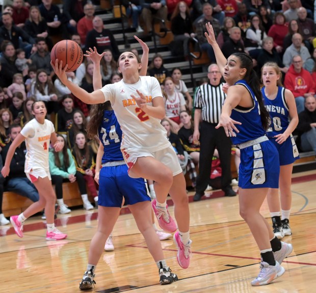 Batavia's Brooke Carlson (2) scoops in a layup after splitting the defense of Geneva's Kinsey Gracie (24) and Leah Palmer during a DuKane Conference game in Batavia on Friday, Jan. 26, 2024.