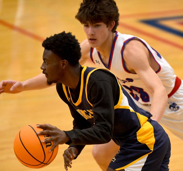 Round Lake's Jaquan Jamerson (11) drives past Lakes' Patrik Dortch (23) on his way to the lane. Lakes High School's boys basketball team defeated Round Lake 66-47 in Lake Villa, Saturday afternoon, Dec. 14, 2024 (Rob Dicker / for the News-Sun)