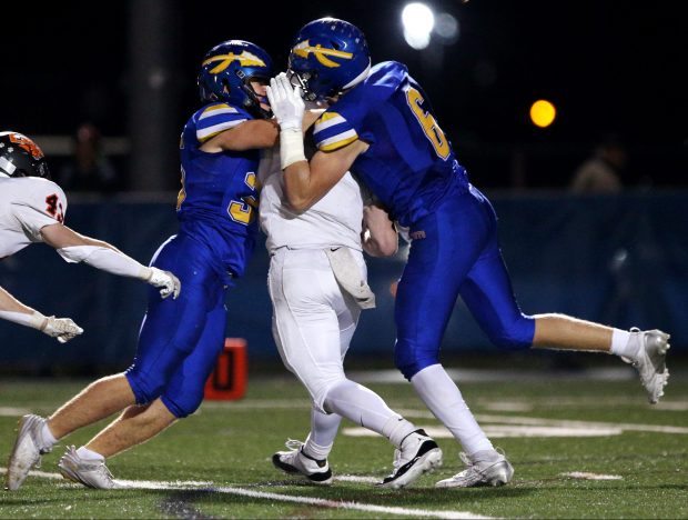 Lake Forest's Timotei Dan (left blue) and Finn Goodman (6), sack Libertyville quarterback, Quinn Schambow (middle), during the game on Friday, Oct. 18, 2024, in Lake Forest. (Mark Ukena/for the Lake County News-Sun)