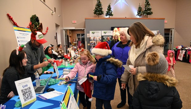 On right, the Wrona family of Round Lake stops at community and vendor tables at the Village of Round Lake Beach's Supper with Santa and Craft Fair on Dec. 5, 2024 in Round Lake Beach. (Karie Angell Luc/Lake County News-Sun)