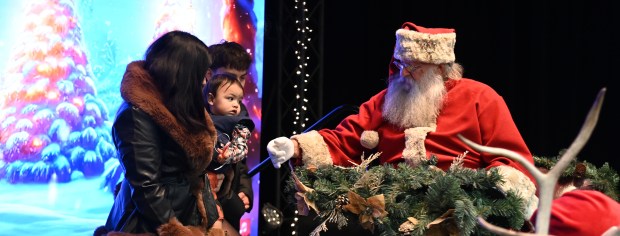 Santa Claus reaches out to Camilo Perez, 1, of Round Lake in the company of the tot's parents Yasmine Figueroa and Chris Perez at the Village of Round Lake Beach's Supper with Santa and Craft Fair on Dec. 5, 2024 in Round Lake Beach. (Karie Angell Luc/Lake County News-Sun)