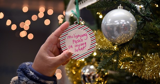 Putting a handmade ornament on the positivi-tree Is Rosielyn Sheridan at the Christmas Tree Lighting at the Zion Park District Leisure Center in Zion on Dec. 13, 2024. (Karie Angell Luc/Lake County News-Sun)