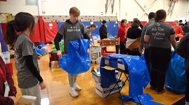 Opening a blue bag for a patron is volunteer Evan Keppler of Barrington at Barrington Giving Day's Winter Event on Dec. 14, 2024 at Station Middle School (215 Eastern Ave.) in Barrington. (Karie Angell Luc/Pioneer Press)