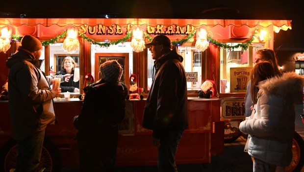 People wait their turn to obtain free popcorn from the Sunset Foods trolley at Illuminate Northbrook on Nov. 22, 2024 in downtown Northbrook. (Karie Angell Luc/Pioneer Press)