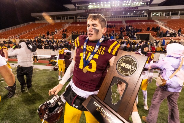 Loyola's Ryan Fitzgerald (15) walks on the field with the Class 8A state championship trophy after defeating York at Hancock Stadium in Normal on Saturday, Nov. 30, 2024. (Vincent D. Johnson / for the Pioneer Press)