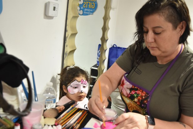 Victoria Duran gets her face painted by Tiffany Early at Angel's Closet's one-year anniversary and community party. Early was also once a single mom and beneficiary of store owner Angelita Bracero's hospitality and last week she helped provide entertainment for the event. (Jesse Wright/Pioneer Press)