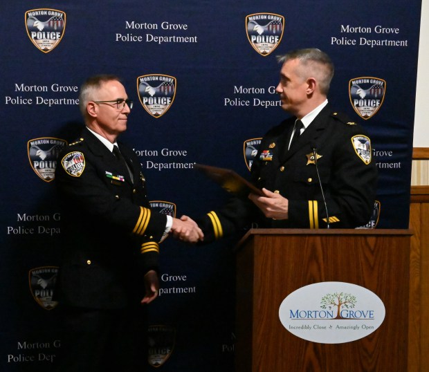 From left to right, is retiring Morton Grove Police Chief Michael T. Simo being recognized by incoming Morton Grove Police Chief Mike Weitzel at the Morton Grove Village Board of Trustees meeting on Nov. 26, 2024. (Karie Angell Luc/Pioneer Press)