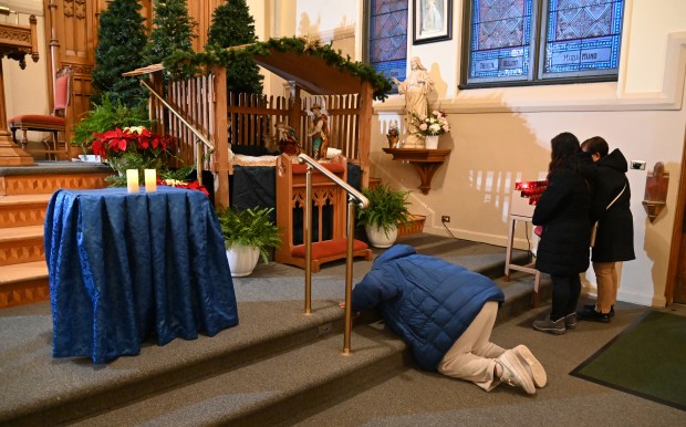 A person prays along the steps in front of the manger after mass at Simbang Gabi 2024 on Dec. 16, 2024 at Saints Peter and Lambert Parish (St. Peter Chapel) in Skokie. (Karie Angell Luc/Pioneer Press)