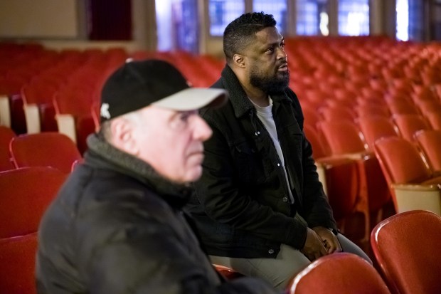 Writer and director of "The Exiles," Chris Jamerson, on right, watches his movie on-screen for the first time with Hoosier Theater owner John Katris ahead of the Sunday premiere of his movie at The Hoosier Theater in Whiting on Friday, Dec. 6, 2024. (Kyle Telechan/for the Post-Tribune)