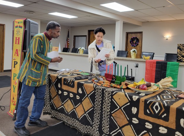 Mariah Smith, right, confers with Kwabena Rasuli before she lights the first Kwanzaa candle representing Umoja, or unity, during a Kwanzaa celebration at the Calumet Township Multipurpose Center Dec. 26, 2024. (Michelle L. Quinn/Post-Tribune)