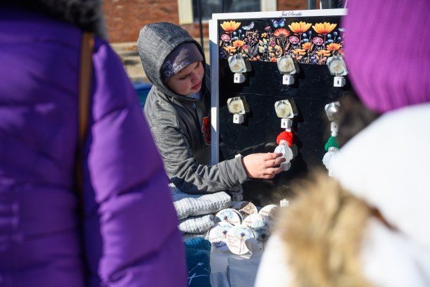 Zax Weaver, 10, one of two brothers who make up the Lake Brothers Wish Company, points out dandelion and snowman night lights to visitors to his family's booth at the Chesterton Holiday Market on Saturday, Dec. 7, 2024. (Kyle Telechan/for the Post-Tribune)